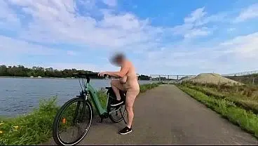 A busty mom rides her bike completely naked on a public path.