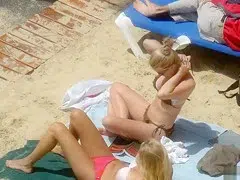 Irresistible gals enjoy sunbathing at a sandy beach